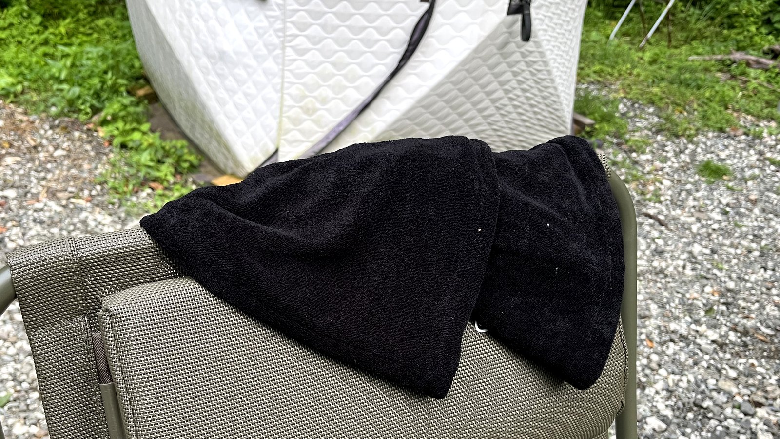 使ったあと、外気浴チェアの背にかけて干している濡れたサウナハット。奥はミキタオサウナのテントサウナ